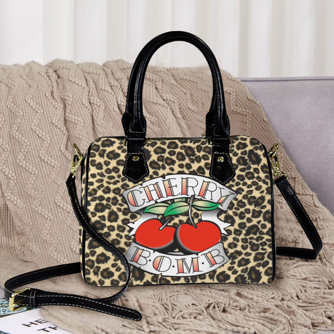 Cherry Bomb Handbag featuring a leopard print design with bold cherry graphics, perfect for adding a stylish touch to any outfit.