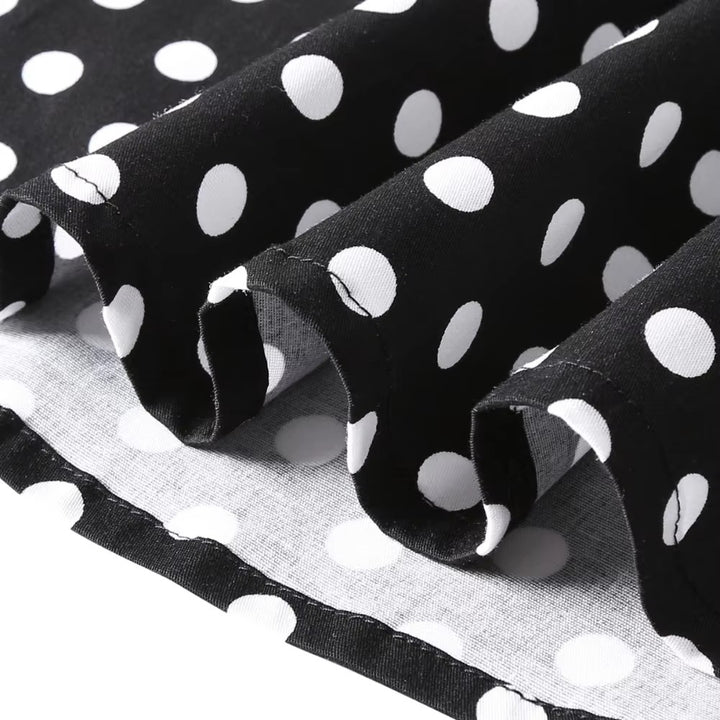 Close-up of black fabric with white polka dots showcasing the texture and ruffle design of a vintage dress.