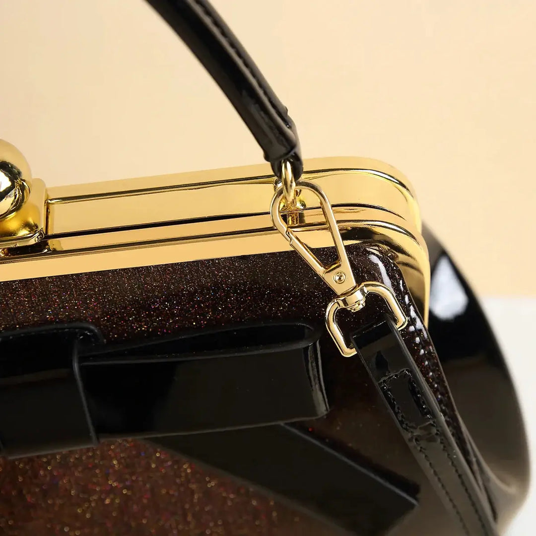 Close-up of the Chocolate Patent Rockabilly Handbag showcasing its chic handle and glossy gold kiss-lock clasp.