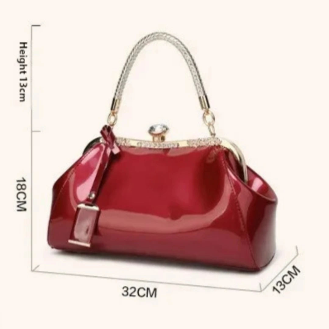 Elegant red patent handbag with rhinestone lock and metal handle, measuring 32CM wide and 18CM tall.