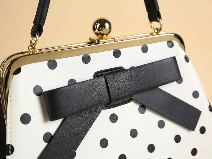 Close-up of a black polka dot rockabilly handbag with a bow and kiss-lock closure, showcasing vintage style.