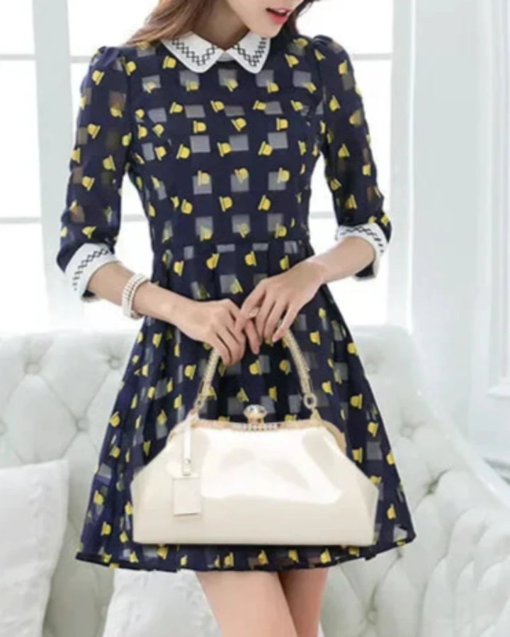 Stylish woman in a patterned dress holding a white patent handbag, showcasing modern fashion and elegance.