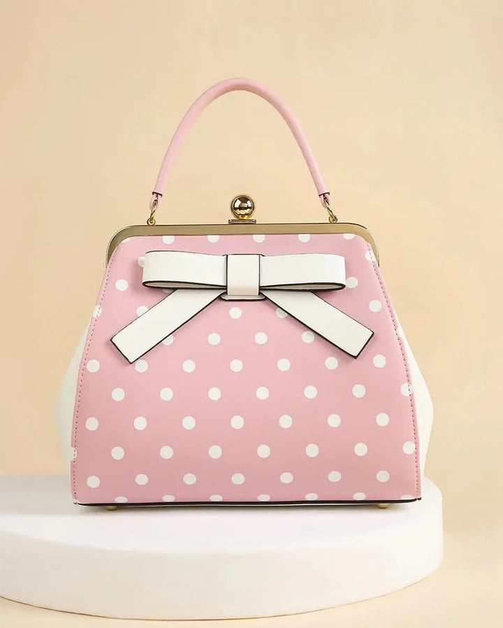 Pink polka dot rockabilly handbag with white bow and classic kiss-lock closure, perfect for retro fashion.