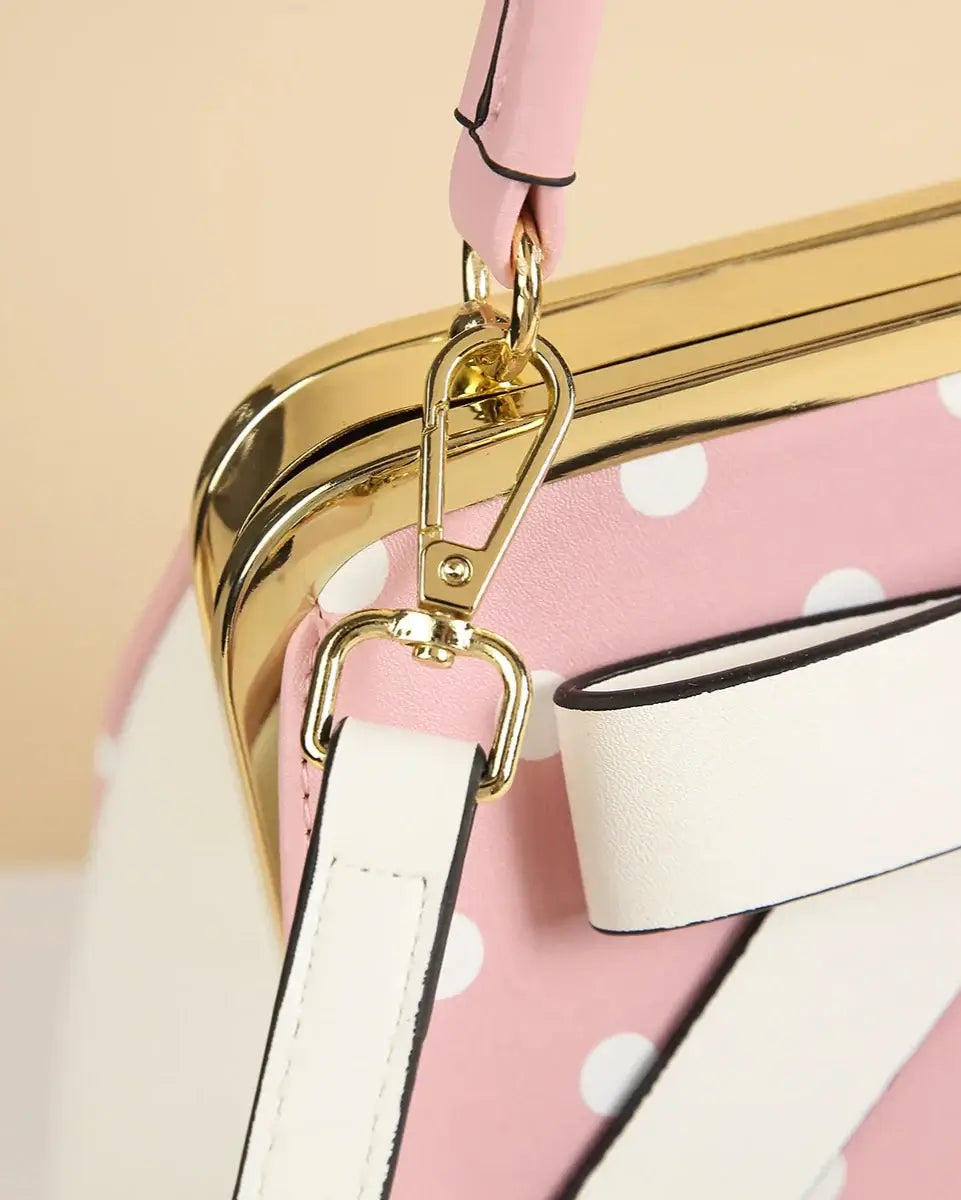 Close-up of pink polka dot rockabilly handbag clasp with shiny gold hardware and white strap.