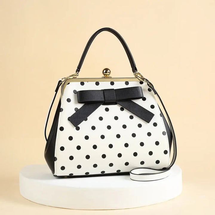 Black and white polka dot rockabilly handbag with structured silhouette and bow detail.