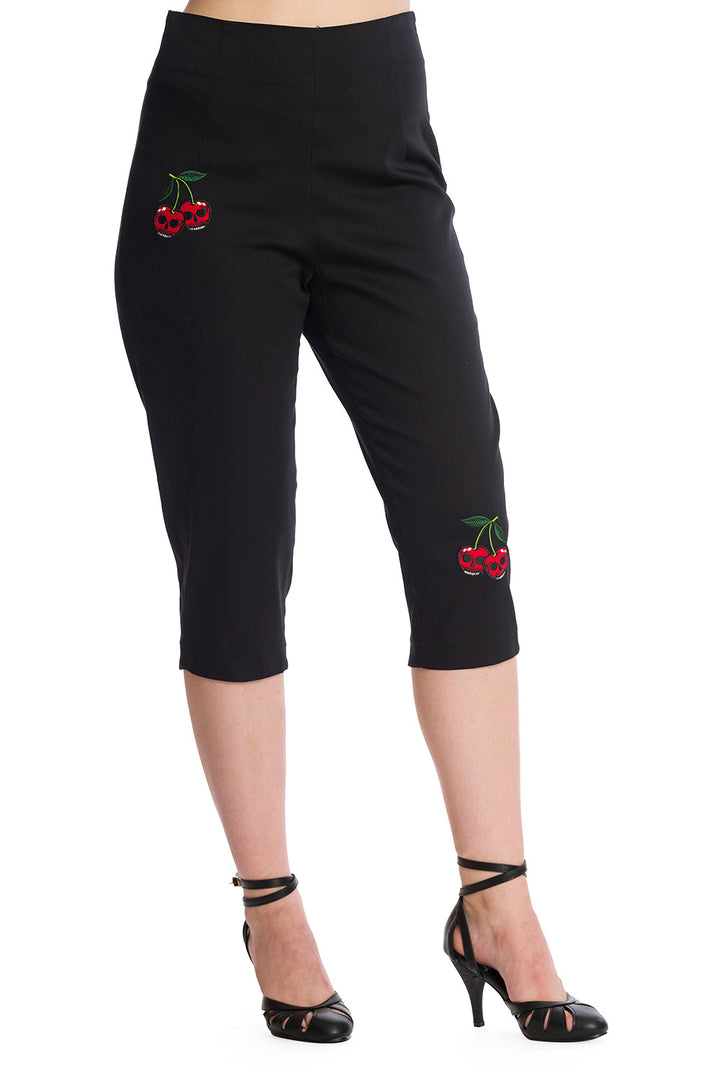 High-waisted black pedal pushers with cherry skull embroidery, styled with strappy heels for a rockabilly look.