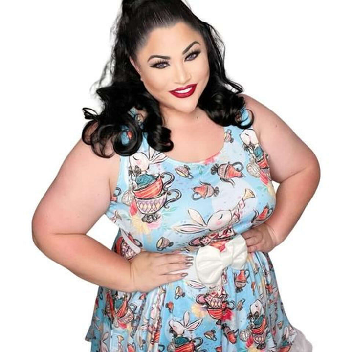 Plus-size model wearing a whimsical Down the Rabbit Hole skater dress with an Alice in Wonderland print and a bow detail.